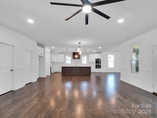 unfurnished living room with ceiling fan, sink, and dark wood-type flooring