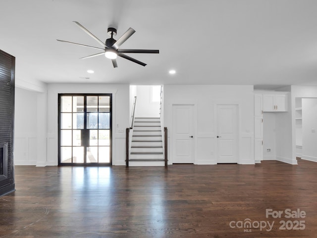 unfurnished living room featuring ceiling fan, a fireplace, and dark wood-type flooring