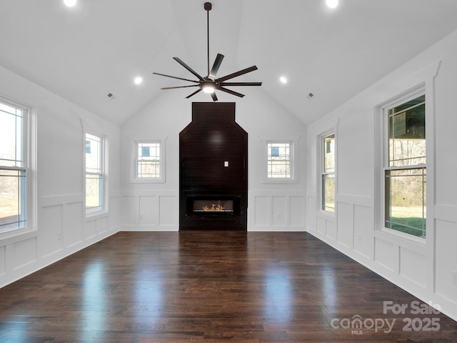 unfurnished living room with a large fireplace, dark hardwood / wood-style floors, vaulted ceiling, and ceiling fan