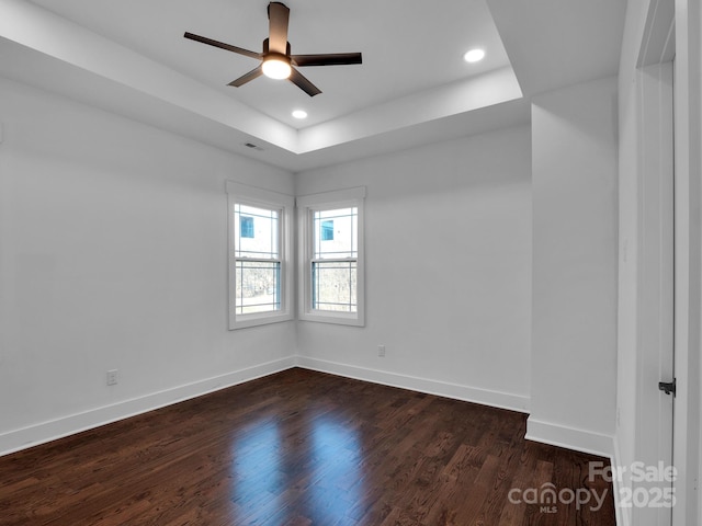 spare room featuring dark hardwood / wood-style flooring, a raised ceiling, and ceiling fan