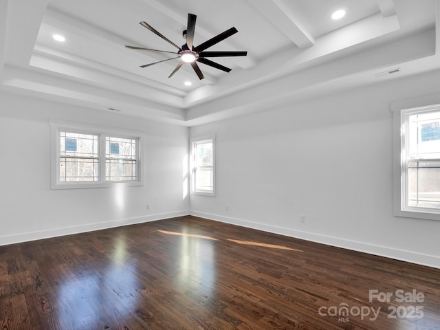 spare room with ceiling fan, a raised ceiling, and dark wood-type flooring