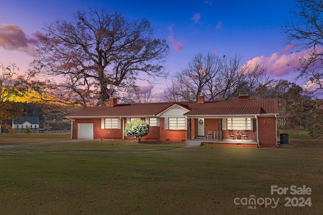 ranch-style home featuring a lawn, central AC unit, and a garage