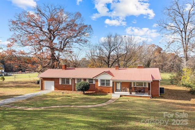 ranch-style house featuring cooling unit, a garage, covered porch, and a front lawn