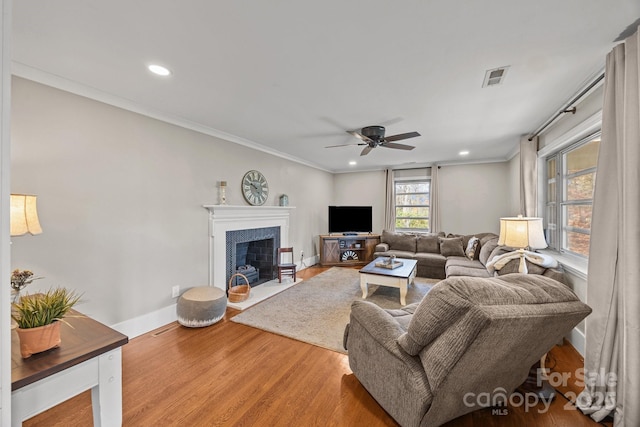 living room with hardwood / wood-style flooring, ceiling fan, and crown molding