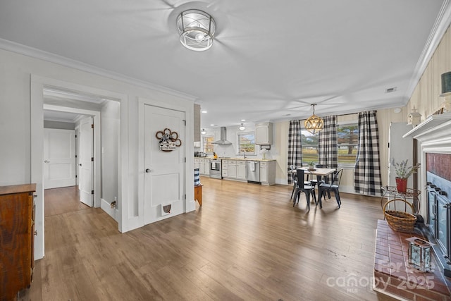 living room featuring crown molding, a fireplace, sink, and hardwood / wood-style flooring