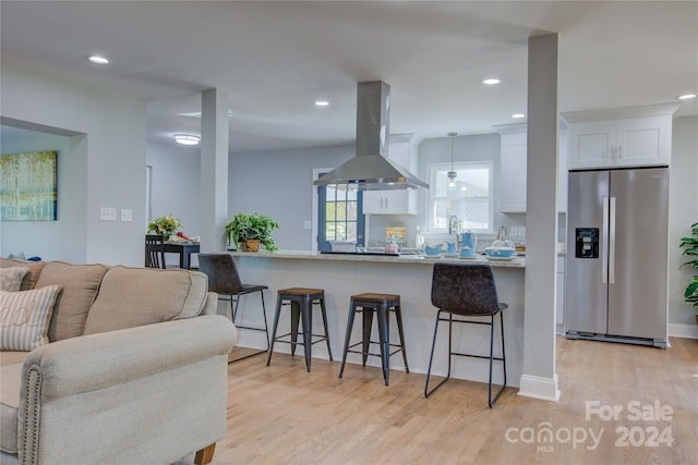 kitchen featuring a breakfast bar, ventilation hood, white cabinets, stainless steel fridge with ice dispenser, and light hardwood / wood-style floors