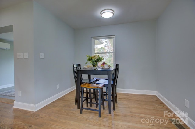 dining area featuring a wall unit AC and light hardwood / wood-style flooring