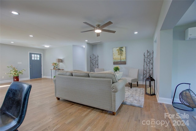 living room with a wall mounted air conditioner, light hardwood / wood-style flooring, and ceiling fan