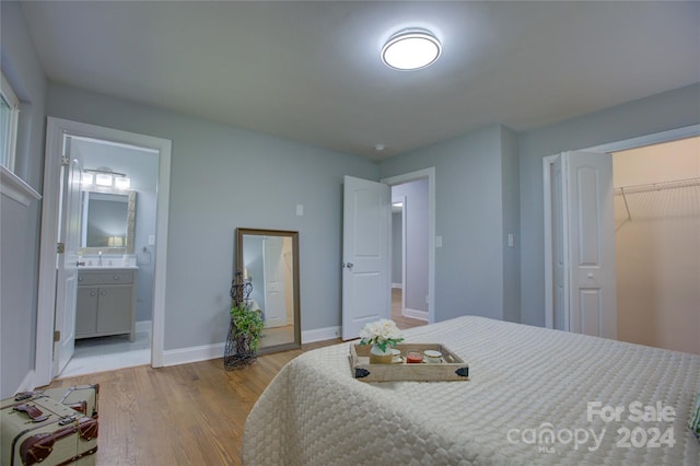 bedroom featuring connected bathroom, a closet, light hardwood / wood-style flooring, and sink