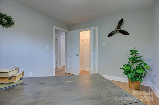 unfurnished bedroom with a walk in closet, a closet, and light hardwood / wood-style flooring