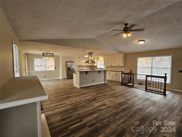 kitchen featuring a center island, dark wood-type flooring, stainless steel refrigerator with ice dispenser, decorative light fixtures, and a breakfast bar area