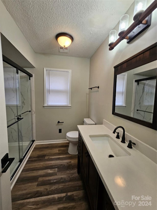 bathroom with hardwood / wood-style flooring, vanity, walk in shower, and a textured ceiling