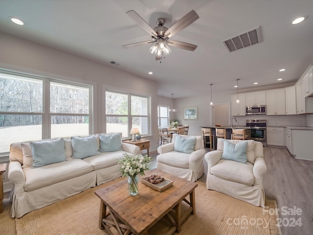 living room featuring light hardwood / wood-style flooring, ceiling fan, and sink