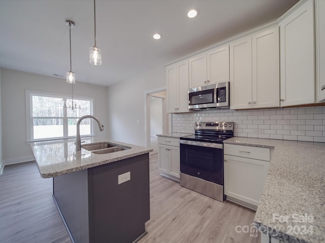 kitchen with white cabinets, sink, appliances with stainless steel finishes, tasteful backsplash, and decorative light fixtures