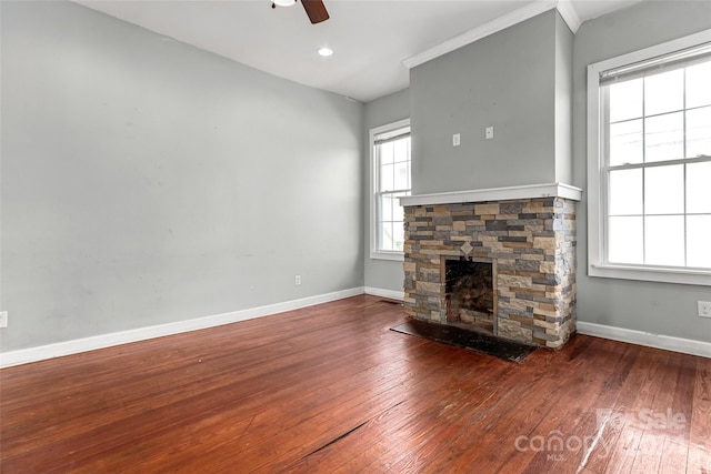 unfurnished living room with hardwood / wood-style floors, ceiling fan, a healthy amount of sunlight, and a stone fireplace