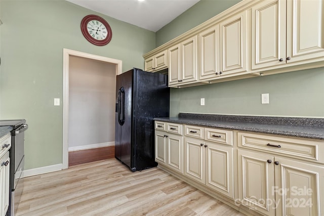 kitchen featuring cream cabinets, light hardwood / wood-style floors, black fridge, and stainless steel electric stove