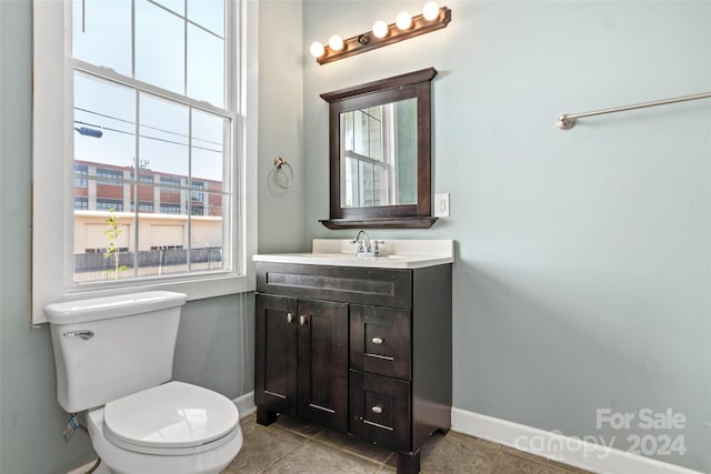 bathroom with tile patterned floors, vanity, toilet, and a healthy amount of sunlight