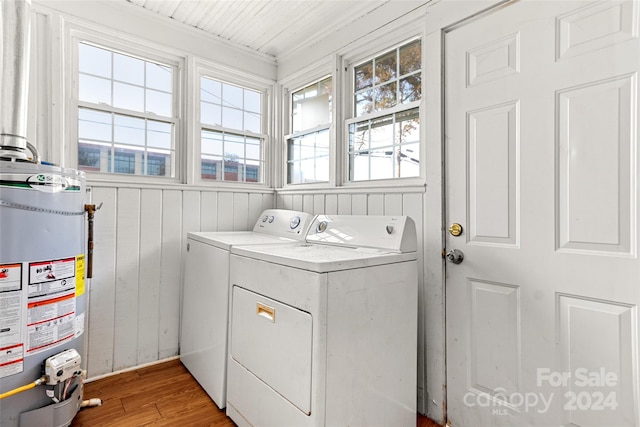 washroom featuring washing machine and clothes dryer, water heater, and a healthy amount of sunlight