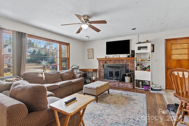 living room featuring a wood stove, a wealth of natural light, ceiling fan, and wood-type flooring