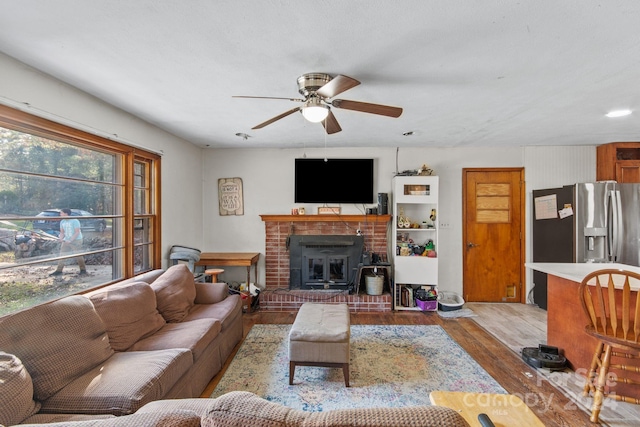 living room with ceiling fan, light wood-type flooring, and a wood stove