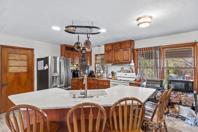 kitchen with sink, stainless steel refrigerator with ice dispenser, a textured ceiling, white electric range oven, and kitchen peninsula