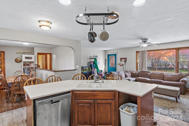 kitchen with stainless steel dishwasher, a kitchen island with sink, ceiling fan, sink, and light hardwood / wood-style floors