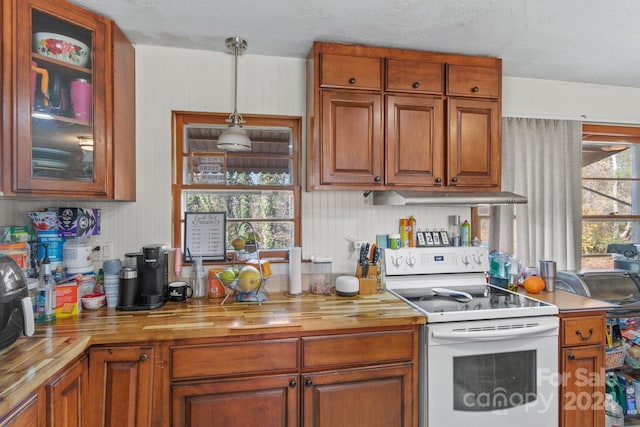 kitchen with a textured ceiling, white range with electric cooktop, decorative light fixtures, and butcher block counters