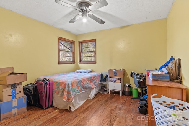 bedroom with ceiling fan, a textured ceiling, and hardwood / wood-style flooring