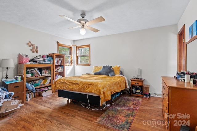 bedroom featuring ceiling fan, wood-type flooring, and a textured ceiling