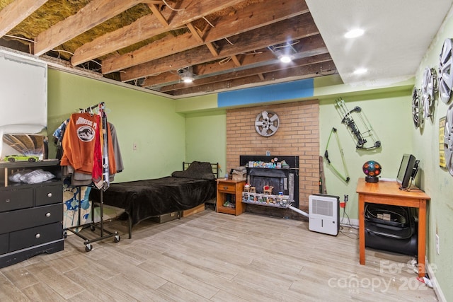 bedroom featuring a brick fireplace and light wood-type flooring