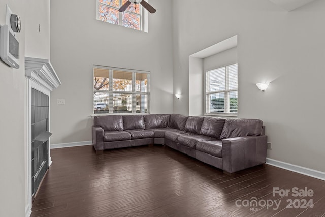 living room featuring a towering ceiling, a wealth of natural light, and dark wood-type flooring