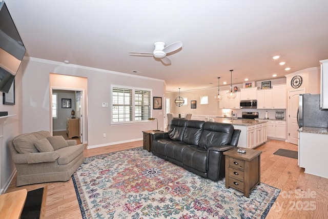 living room with crown molding, ceiling fan, and light hardwood / wood-style floors