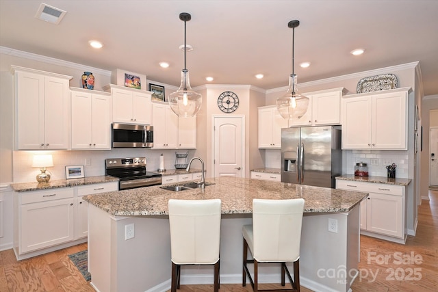 kitchen with an island with sink, stainless steel appliances, sink, and white cabinets