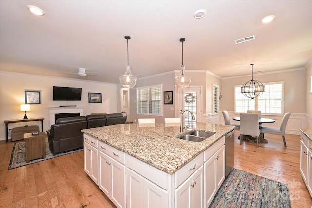 kitchen with pendant lighting, sink, a kitchen island with sink, light hardwood / wood-style floors, and white cabinets