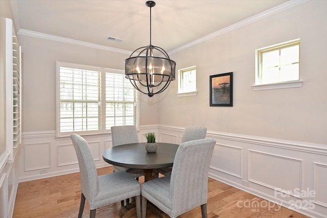 dining room with crown molding, an inviting chandelier, and light hardwood / wood-style flooring