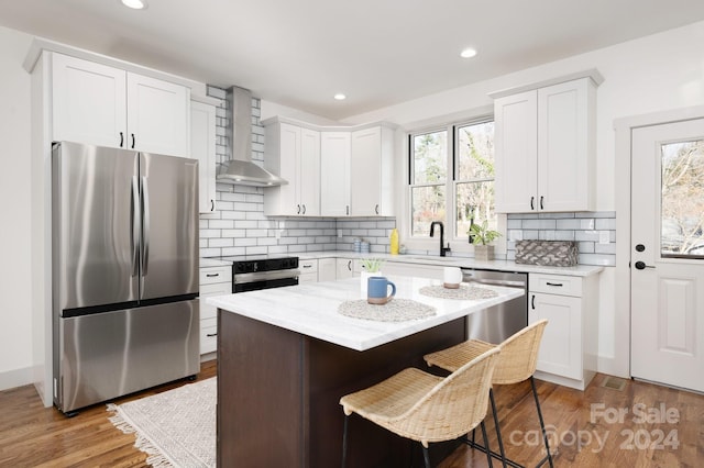 kitchen featuring a center island, stainless steel appliances, white cabinetry, and plenty of natural light