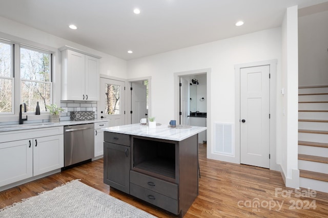 kitchen with dishwasher, a center island, sink, a healthy amount of sunlight, and white cabinetry