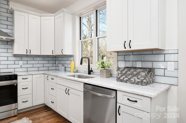 kitchen featuring light stone counters, stainless steel appliances, white cabinetry, and sink