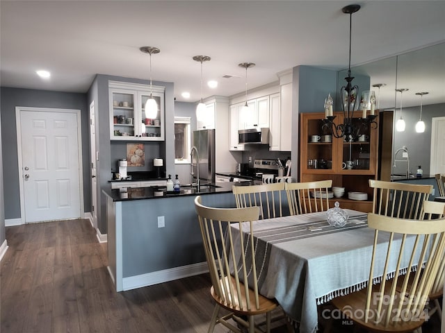 kitchen with pendant lighting, dark hardwood / wood-style floors, white cabinets, and stainless steel appliances