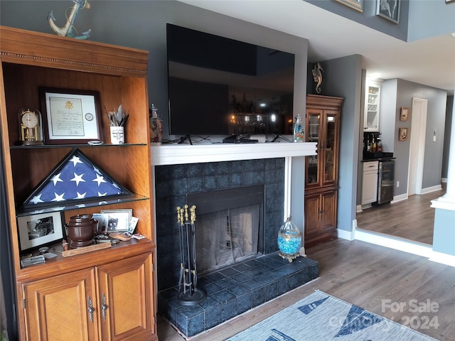 details featuring beverage cooler, wood-type flooring, and a tile fireplace