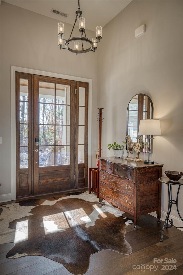 foyer entrance with dark wood-type flooring, high vaulted ceiling, and an inviting chandelier