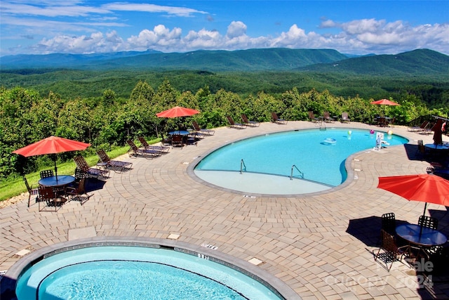 view of swimming pool with a mountain view, a community hot tub, and a patio area