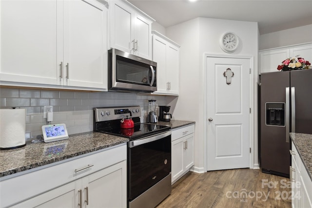 kitchen with stainless steel appliances, white cabinetry, dark hardwood / wood-style floors, and dark stone counters