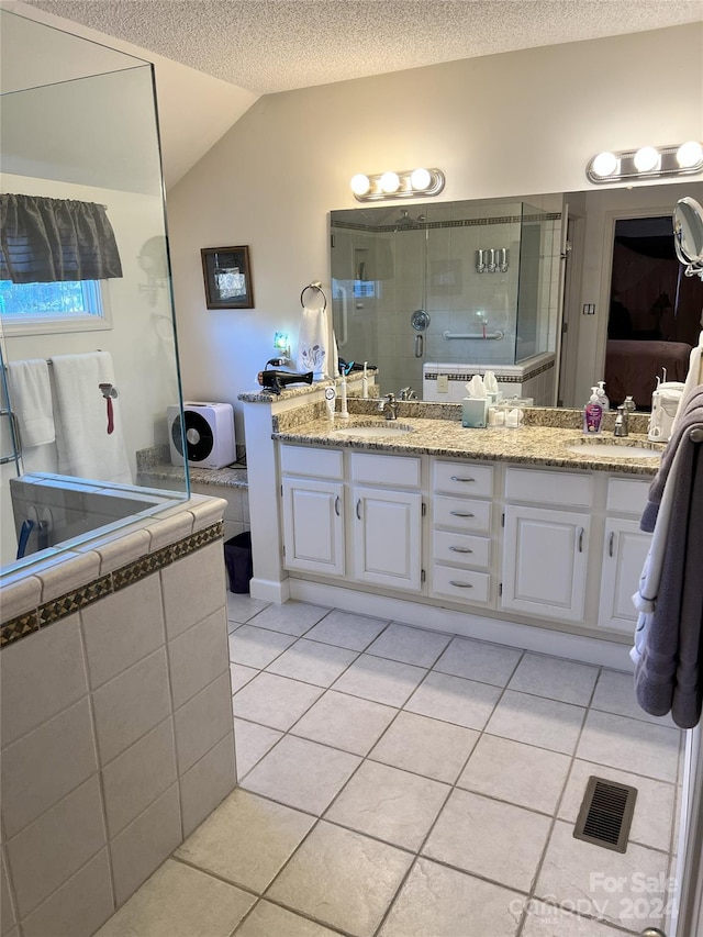 bathroom with tile patterned floors, vanity, a textured ceiling, and vaulted ceiling