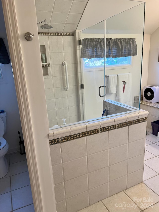 bathroom featuring tile patterned floors, toilet, and a shower with door