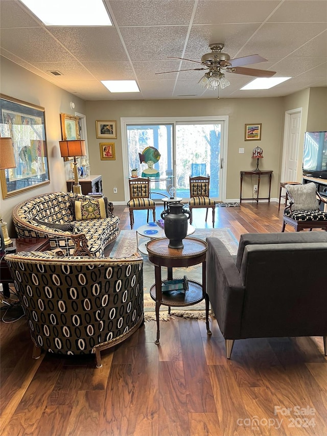 living room with ceiling fan, a drop ceiling, and hardwood / wood-style flooring