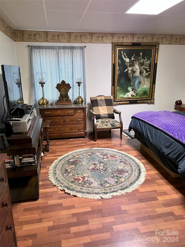 bedroom with a drop ceiling and wood-type flooring