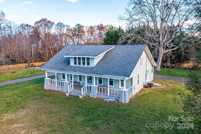 view of front of property featuring central AC, covered porch, and a front lawn