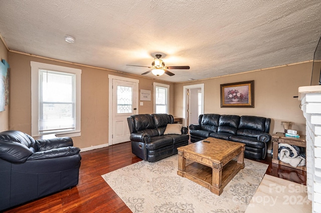 living room featuring a textured ceiling, ceiling fan, ornamental molding, and dark wood-type flooring