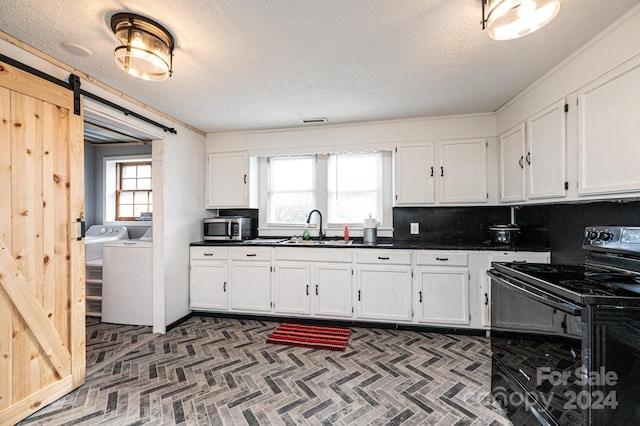 kitchen with washing machine and dryer, plenty of natural light, black range with electric stovetop, and a barn door